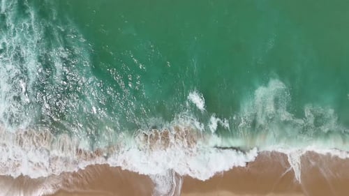 Breathtaking Aerial View of Turquoise Ocean Waves Crashing Gracefully on the Shoreline