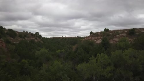 Aerial dolly forward shot of beautiful nature in georgia with a forest, rocks and the cloudy sky in