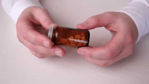 Glass Bottle with Pills in Hands