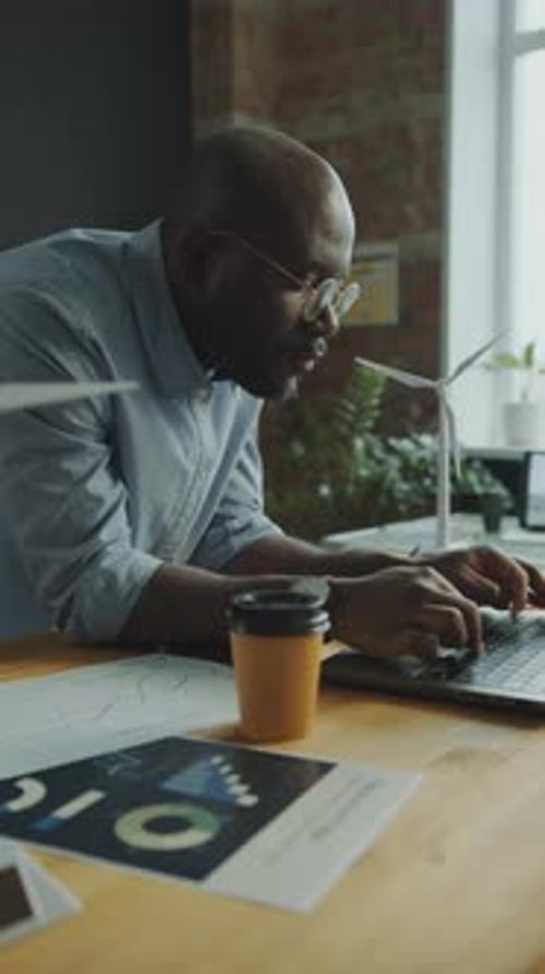 African American Engineer Working on Wind Energy Project on Laptop at Desk