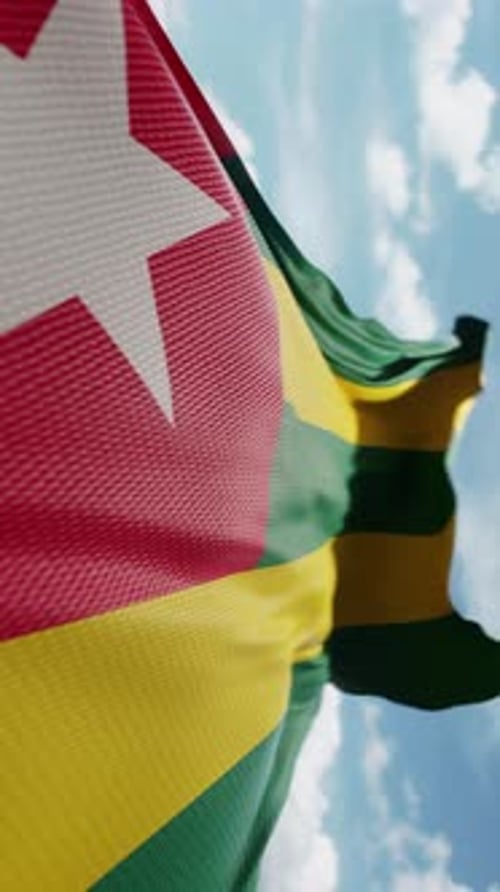 Realistic Togo National Flag Waving in Wind Against Blue Sky