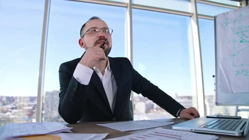 Smiling entrepreneur in office. Portrait of a businessman in glasses sitting at the table w