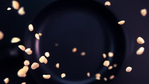 Super Slow Motion of Rotating Roasted Peanuts Falling Onto a Frying Pan