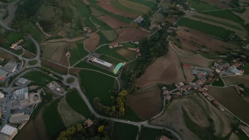 Aerial Shot Following a Paraglider Flying Above the Green Forest and Countryside