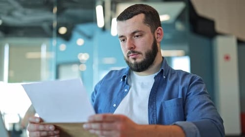 Bearded Man Reads Letter with Surprised Expression