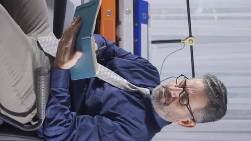 Vertical Video of Elderly businessman working in office using laptop.