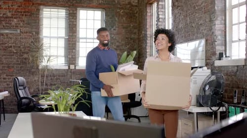 Happy diverse colleagues holding boxes with documents and office items in slow motion