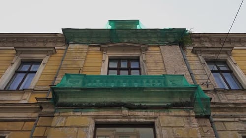 The Historic Building Facade Covered with Green Netting for Restoration Efforts in a Busy Urban Area