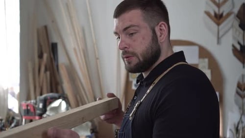 Male Builder or Carpenter with Wooden Plank in Carpentry Workshop