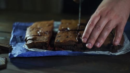 Mann schneidet Kuchen auf Holztisch. Zubereitete Schokoladenkuchenstücke in der Küche