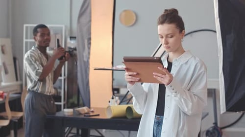Multiethnic Photographer Team Looking at Photos on Tablet PC in Studio