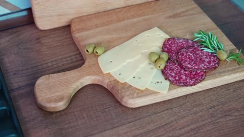 Cutting Board with Salami Cheese and Olives on the Kitchen From Top View