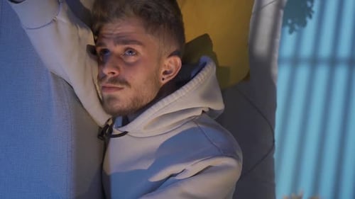 Vertical Video Of Depressed young man lying on sofa at home, thoughtful.