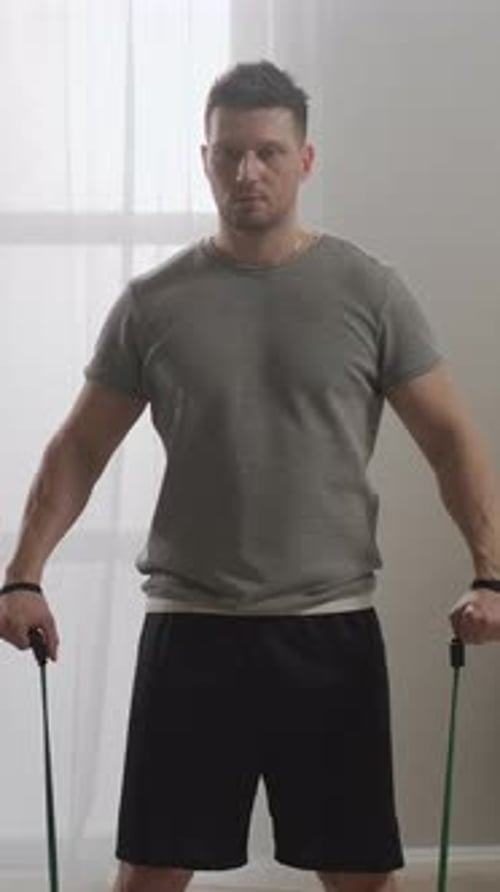 Focused Man Performing Resistance Band Workout at Home Demonstrating Strength Training Exercise