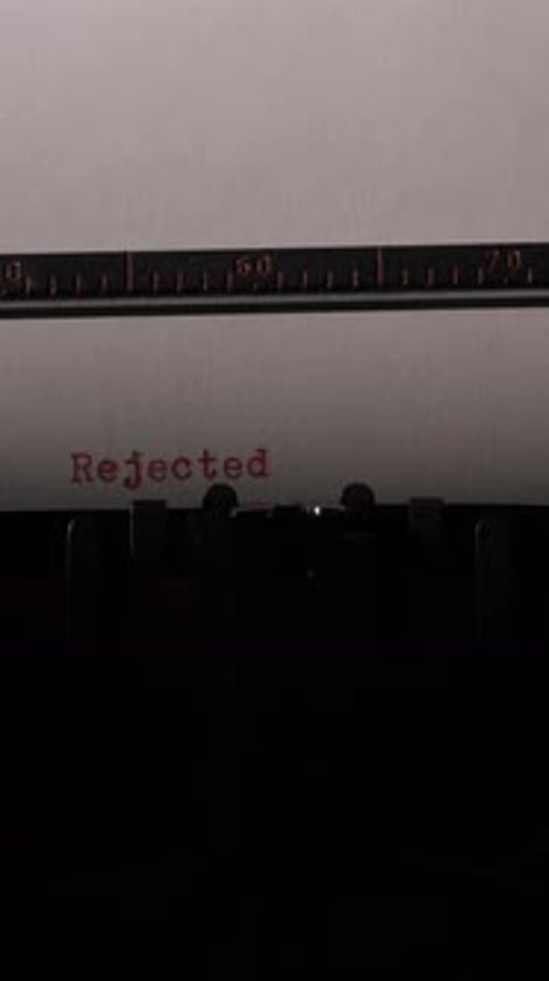 Vertikale Video-Schreibmaschine im Vintage-Stil, die das Wort „Abgelehnt“ mit roter Tinte auf Papier tippt, was Ablehnung symbolisiert