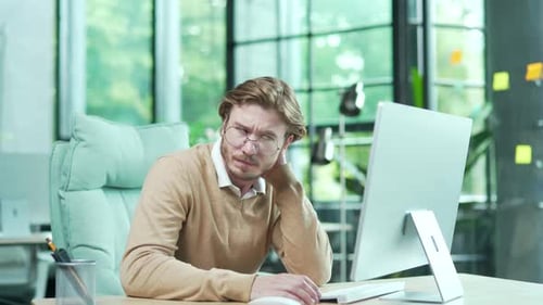 Thoughtful Man Working at a Computer in Office
