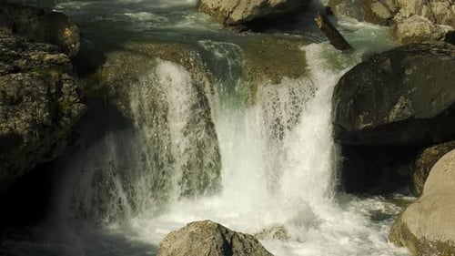 Cold water of mountain stream cascading over rocks, close up