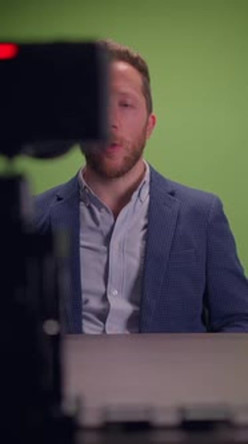 A Professional Male Presenter Engaging Effectively Amidst a Green Screen for Media Productions