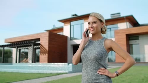 Woman Talking on Phone in Front of Modern House