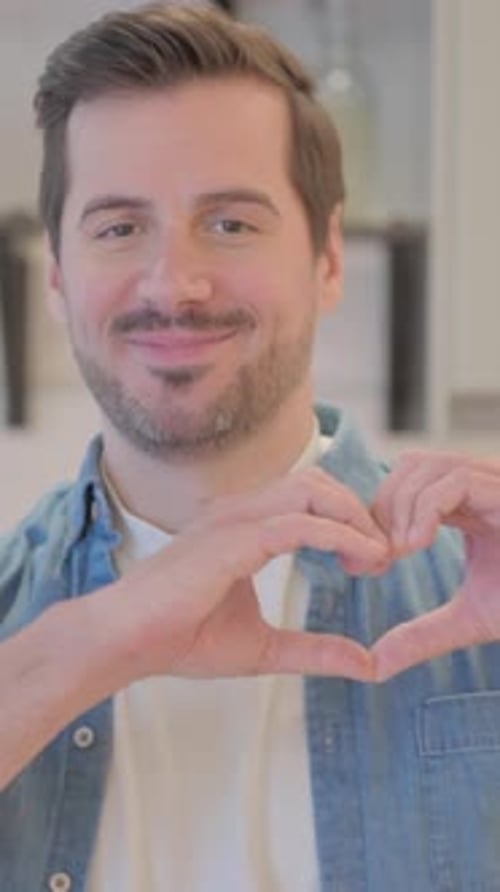 Smiling Man Makes Heart Shape with Hands
