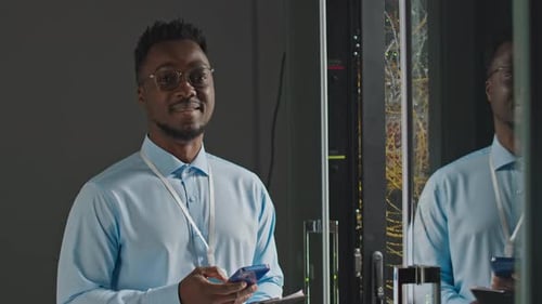 Adult Man in Data Center with Smartphone