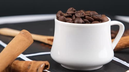 White Mug Filled with Coffee Beans and Cinnamon