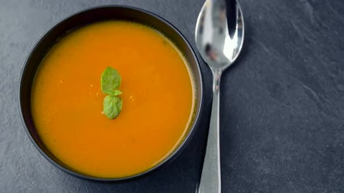 Bowl of orange soup with a metal spoon