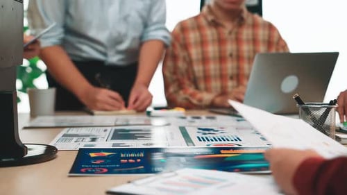 Team Collaborating on Business Data Analysis with Charts and Graphs in Modern Office Environment for