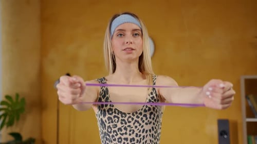 Blonde woman exercising with resistance band at home