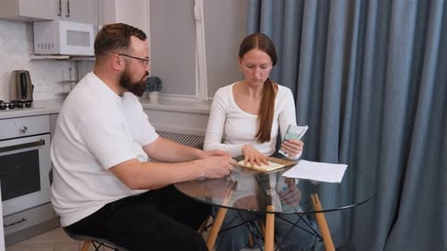 Couple managing domestic budget, counting euro banknotes at home