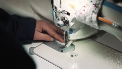 Close-up of a woman's hands sewing fabric on a factory sewing machine to make a cover for a mattress