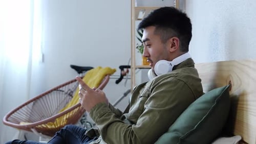 Young Adult Using Phone and Smiling on Bed