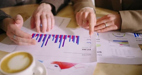 Finanzanalysten betrachten Berichte mit Verkaufsdiagrammen und erörtern die Strategie des Unternehmens in Nahaufnahme