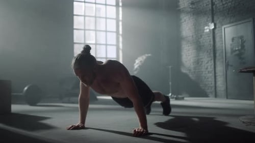 Shirtless athlete training body doing push ups in gym loft building workout
