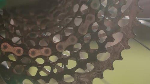Close-up of a bicycle gear and chain, highlighting intricate metallic details and motion