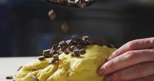 Zeitlupe eines Kochs, der einige Schokoladenstückchen in den Teig gibt, um ein Dessert zuzubereiten. Konzepte von