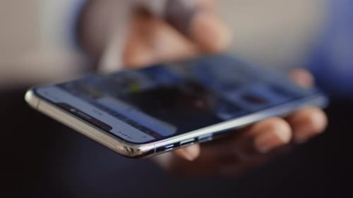 African Guy Scrolling Social Media App on Cellphone Close Up