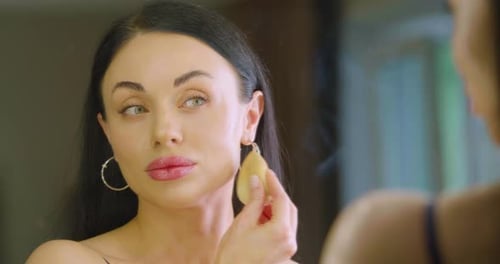 Closeup View of a Caucasian Woman Applying Makeup Foundation in Front of Mirror at Home