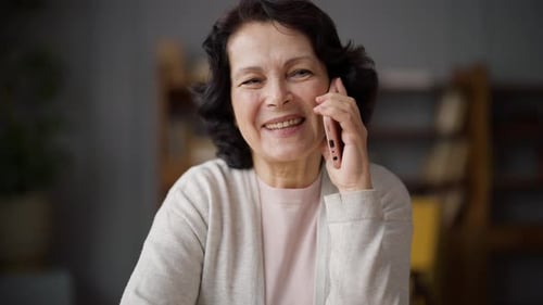 Woman Smiles While Talking On Smartphone Indoors