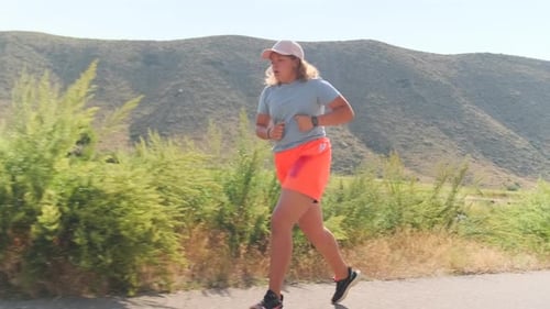 Woman Jogging on Path near Mountain