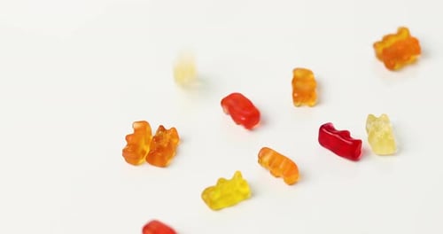 Colorful Gummy Bears Falling onto White Surface