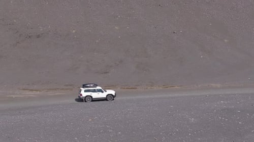 White SUV Driving on Dirt Road in Volcanic Landscape of Iceland