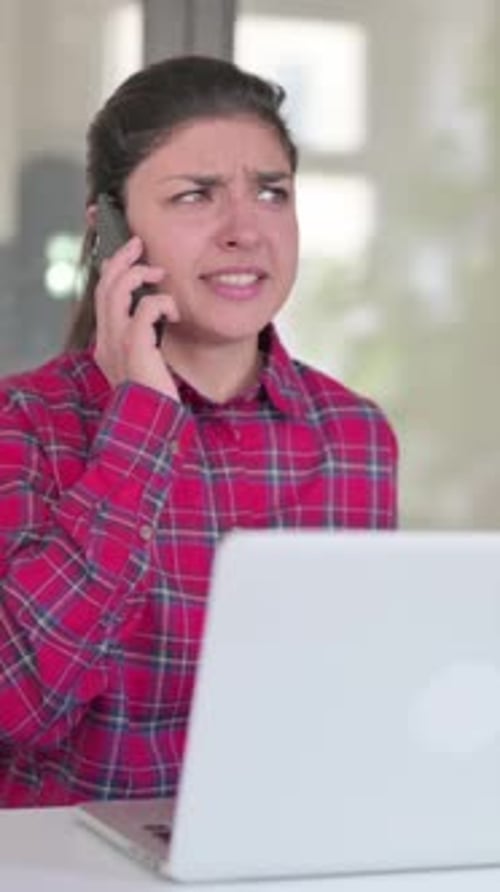 Woman Expressing Frustration While Using Phone and Laptop