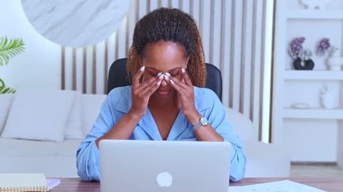 Woman Working at Laptop Massaging Temples Indoors
