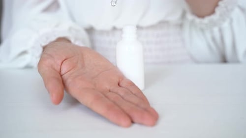 Serum Drops from Pipette onto Woman's Hand