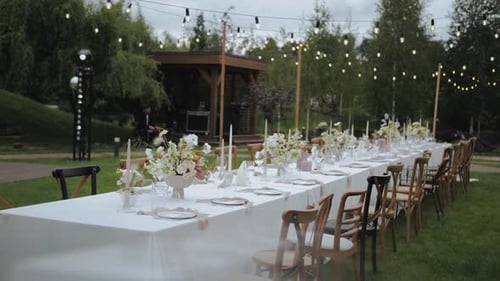 View of Festive Decorated Dinner Table with a Vase of Bouquet of Pastel Fresh Flowers and Greens