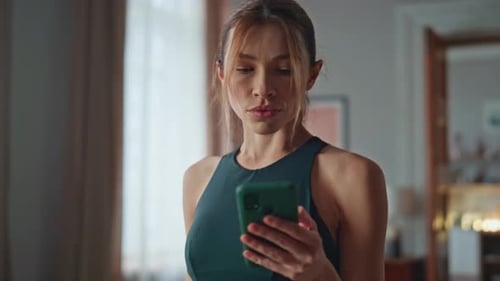 Woman Using Phone While Drinking Water at Home