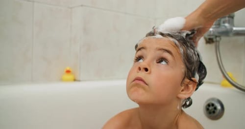 Genießen Sie die Freude am Baden, während eine Mutter die Haare ihres Kindes zärtlich reinigt
