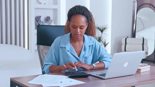 Young Happy African American Business Woman Calculates Profit on Calculator