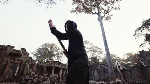 Mysterious Warrior Poses with Sword among Ancient Ruins